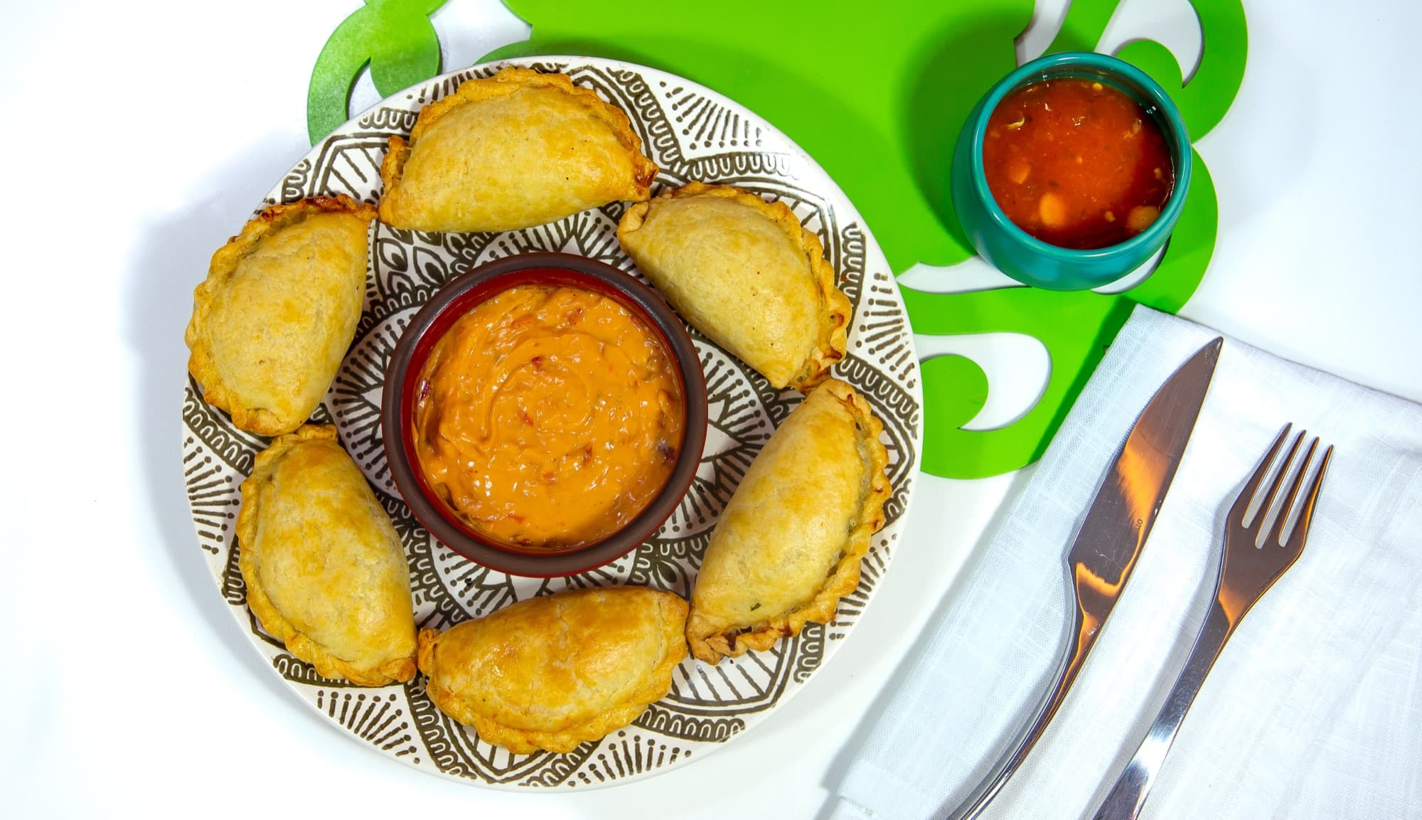 Seis empanadas Kamimo horneadas alrededor de una salsa