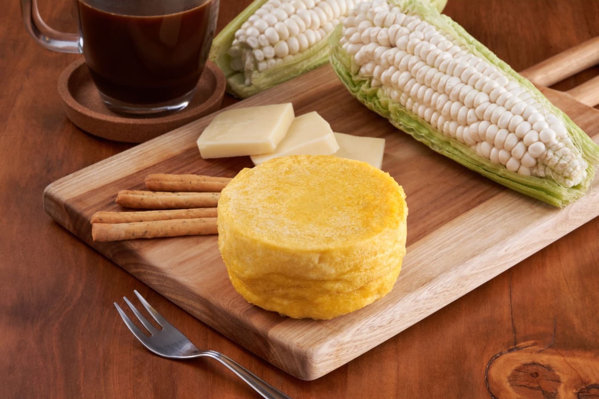Pastel de choclo Kamimo sobre una tabla de madera, junto a choclo y queso