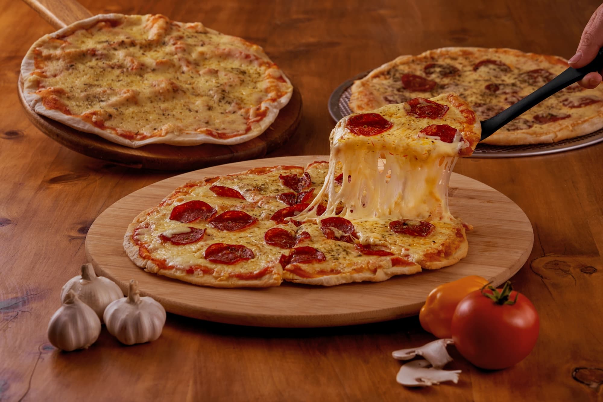 Pizzas Kamimo de pepperoni y queso, con una porción estirando el queso